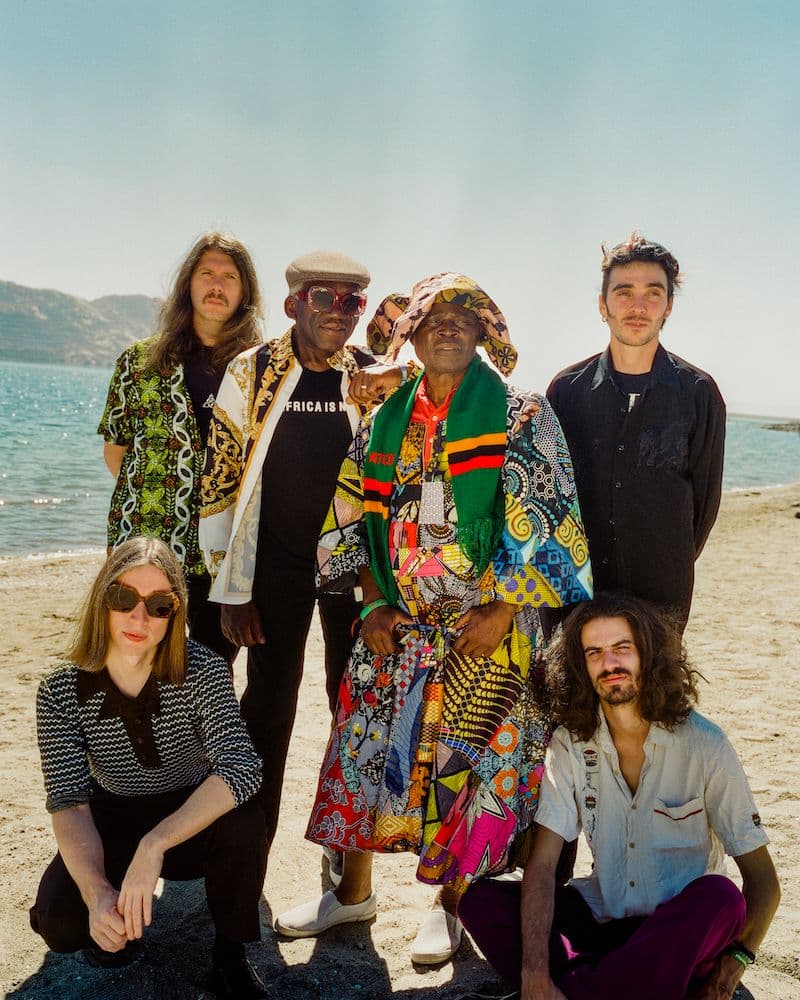 Band members posing together on the beach.